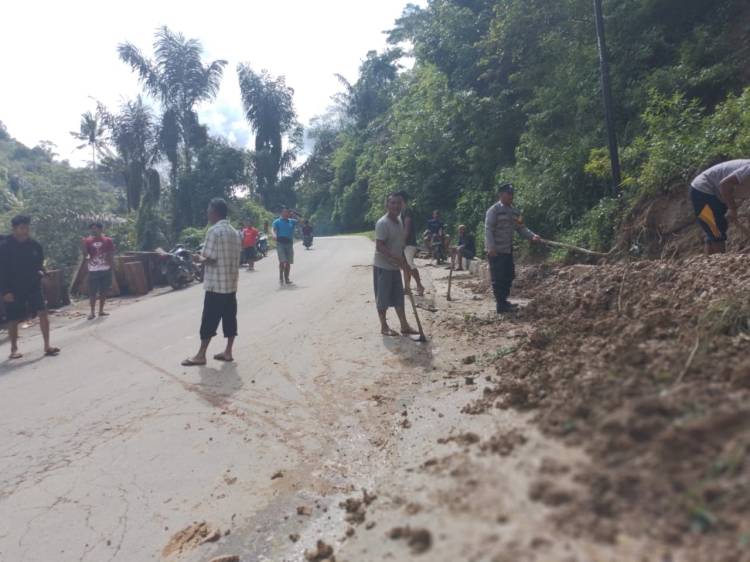Bhabinkamtibmas Bantu Warga Bersihkan Material Longsor dari Jalan