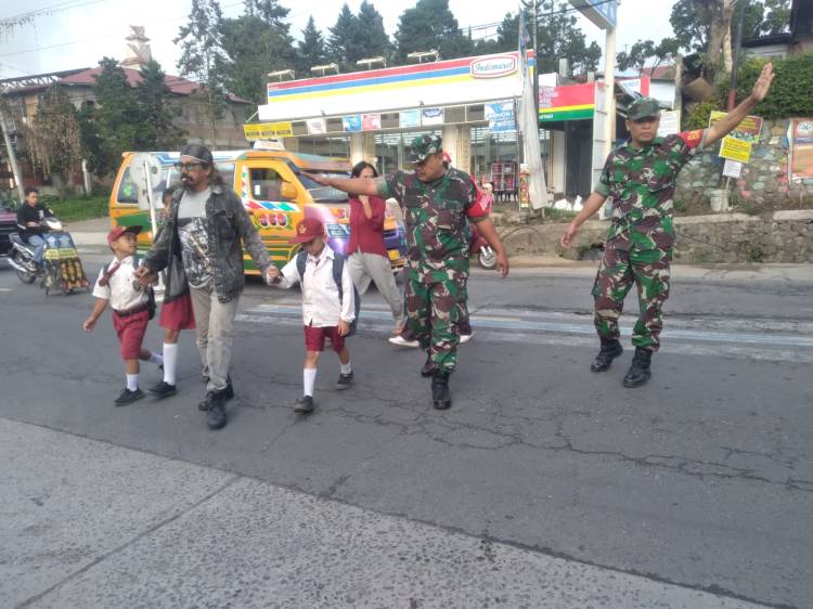 Bentuk Kepedulian TNI Kepada Masyarakat , Babinsa Koramil 03/Berastagi Bantu Seberangkan Anak Sekolah