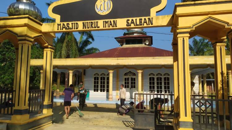 Anggota Satgas TMMD Goro bersama warga bersihkan halaman masjid.