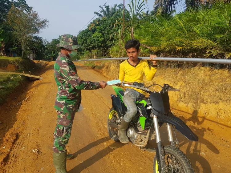 Anggota Satgas TMMD bagikan masker pada warga.