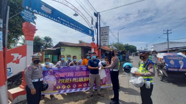Kasatlantas Polres Pelabuhan Belawan Bagi Helm di kampung Tertib Berlalulintas